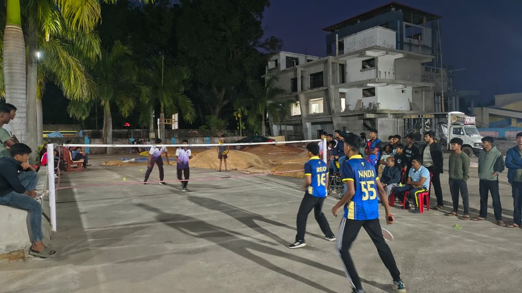 Students playing badminton under floodlights